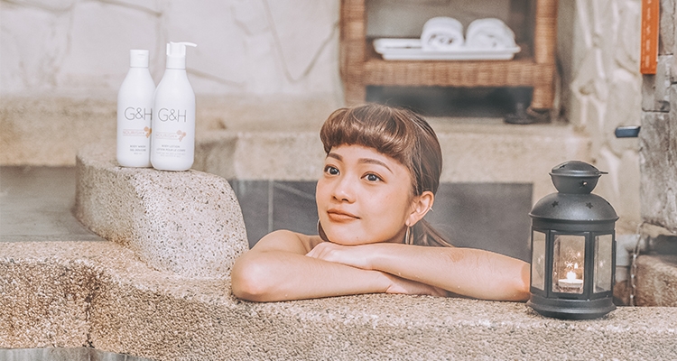 Woman relaxing in a bath tub with G&H body care products 