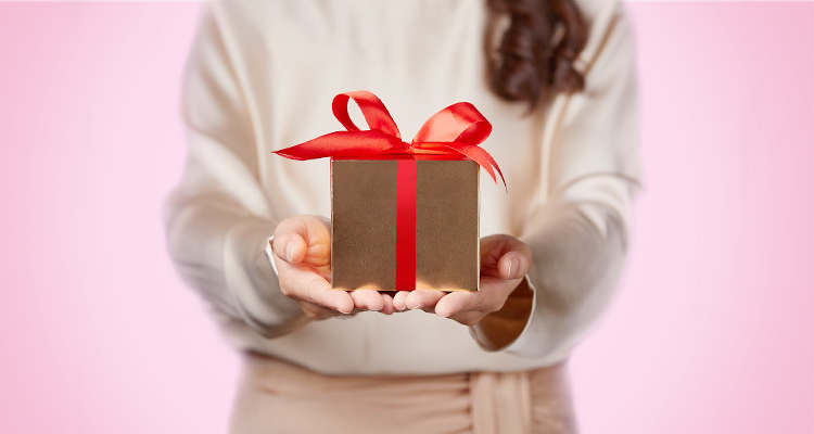 Woman holding gift box tied with red ribbon 