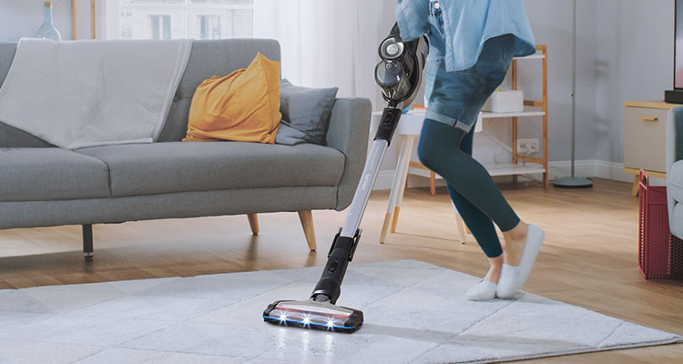 Lifestyle image of a woman vacuuming with the Philips SpeedPro Max Aqua Cordless Stick Vacuum Cleaner FC6903 
